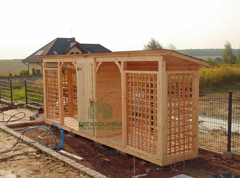 jasna pergola stojąca przy czarnym płocie