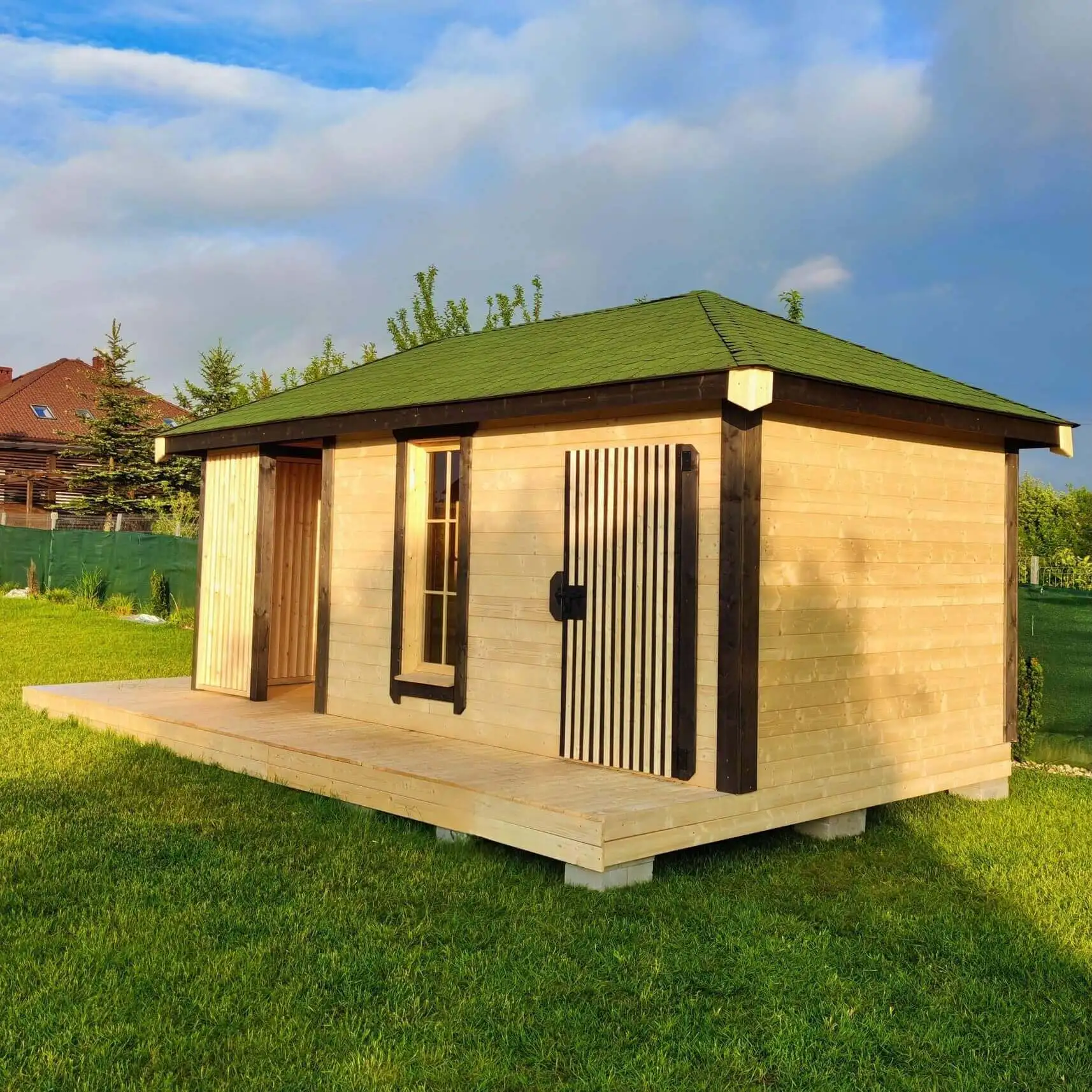 Drewniana altana ogrodowa z przeszklonymi drzwiami i oknami, czterospadowym dachem oraz dekoracyjnym wejściem. W stylu loft.  