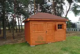 drewutnia z bordowym dachem stojąca na trawie