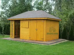 Zolta drewutnia z ciemnym dachem na kostce brukowej