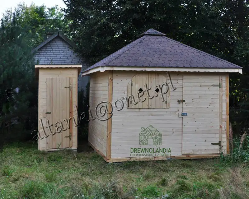 jasnobrazowa drewutnia z ciemnym dachem stojaca na trawie