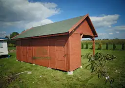 drewutnia z ciemnym dachem stojąca na trawie