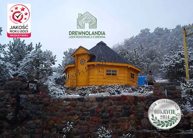 domek letniskowy z czarnym dachem wśród drzew w zimie