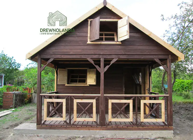 ciemnobrązowy domek letniskowy z tarasem i otwartymi oknami