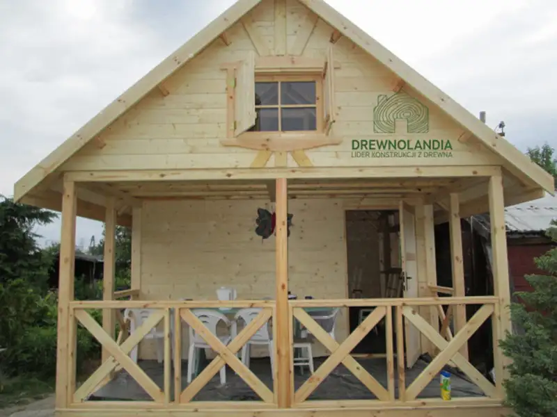 jasnobrązowy domek letniskowy z tarasem i poddaszem przy drzewach