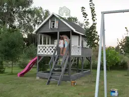 szary domek letniskowy dla dzieci z rozowa zjezdzalnia i schodkami